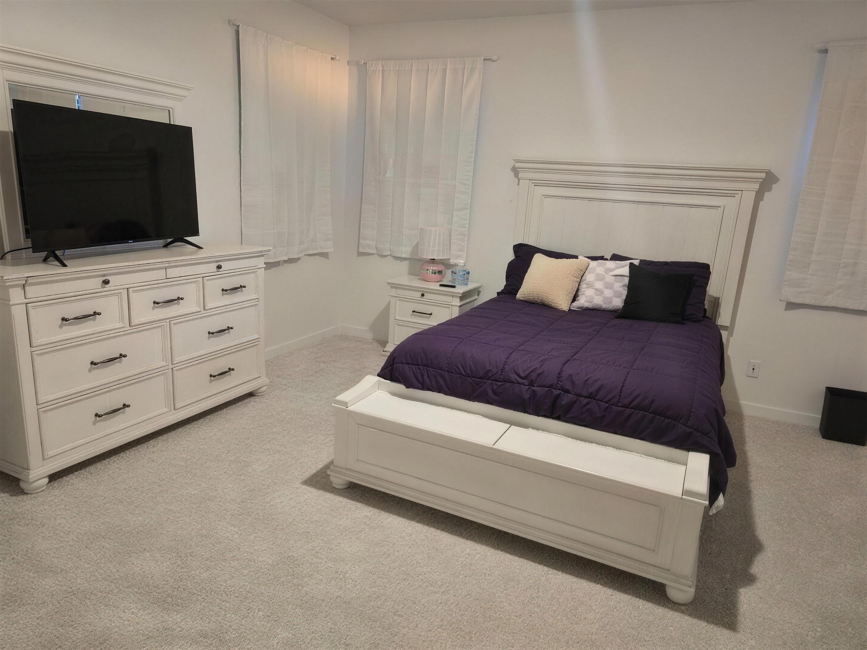 Primary suite with queen bed, smart TV, and full dresser