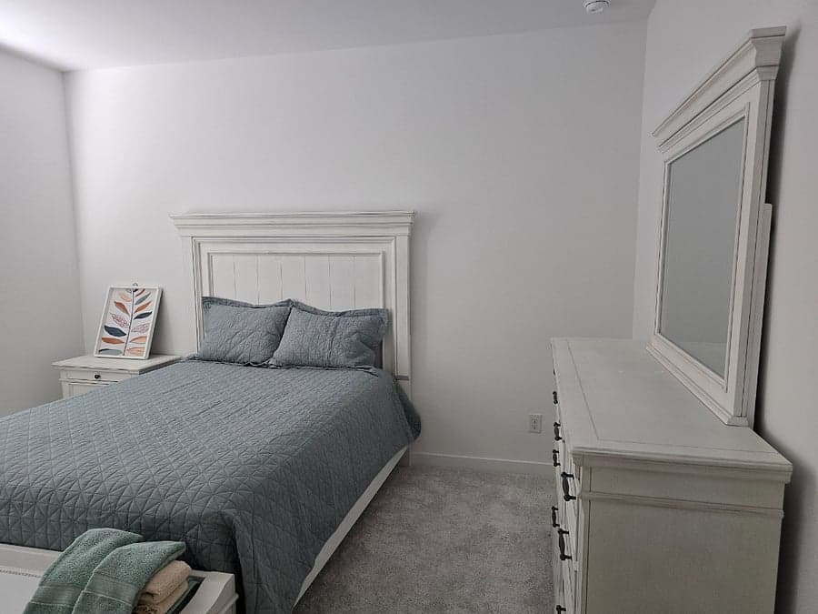 Bedroom with queen bed, dresser, and vanity mirror