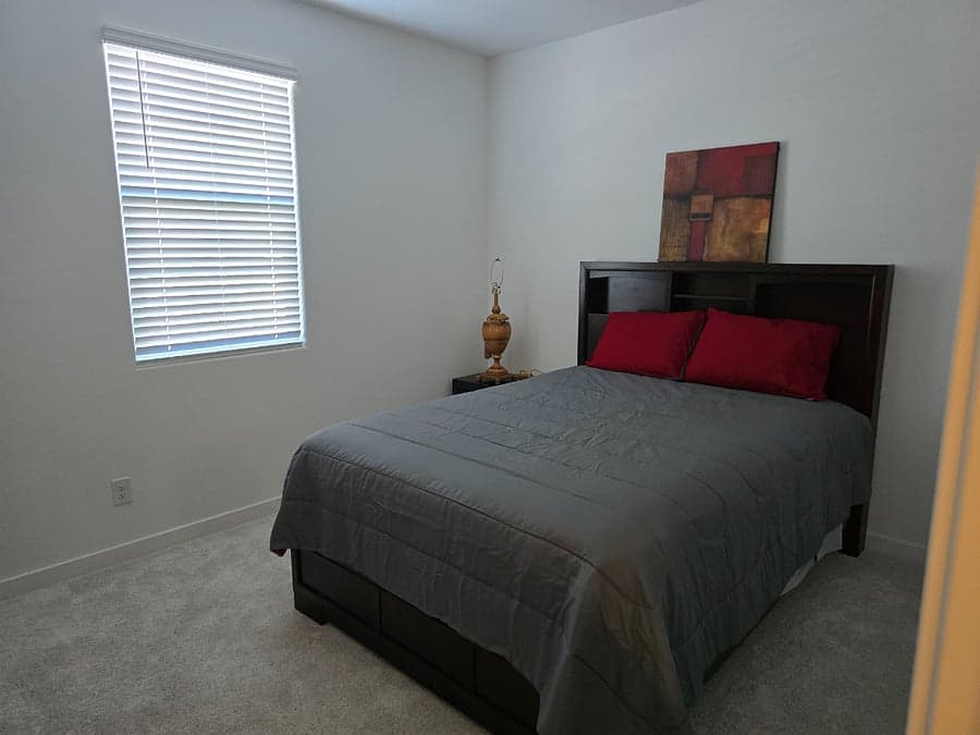 Bedroom with queen bed and window blinds
