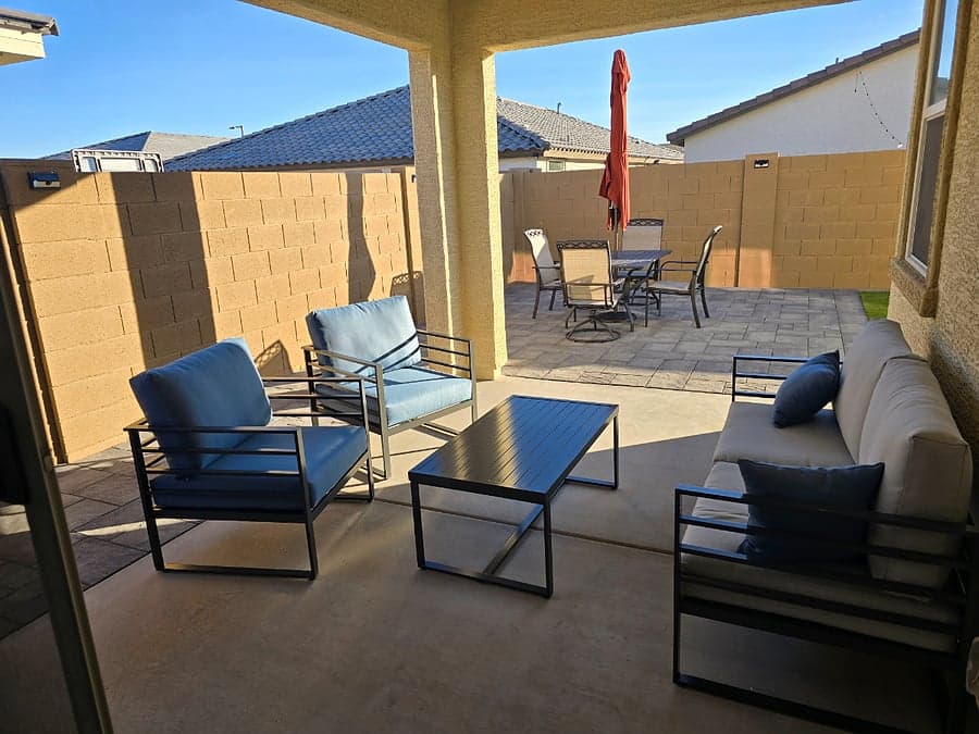 Covered backyard patio with outdoor lounge seating and dining set